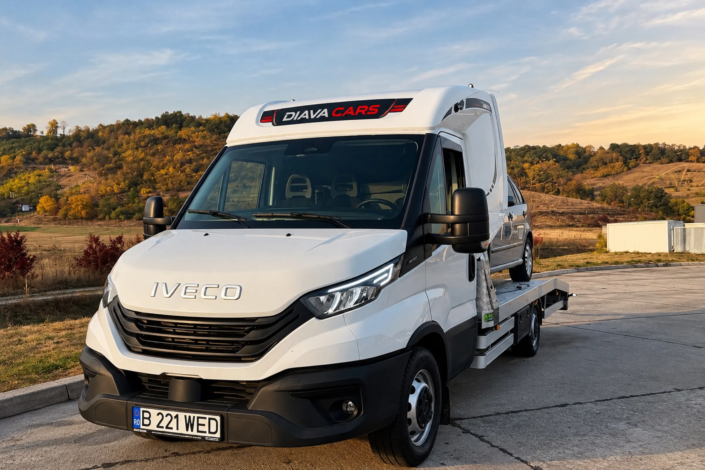 Iveco Daily Diava Cars văzut din față, cu inscripția Diava Cars pe parasolar și un autoturism pe platformă